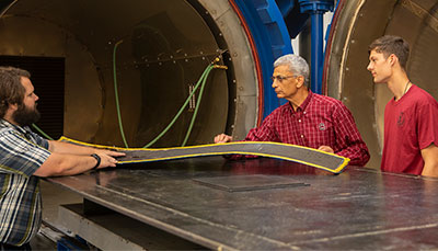 Three people discussing and examining a physical material.