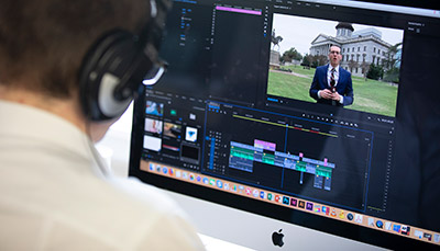 Student editing video on desktop computer.