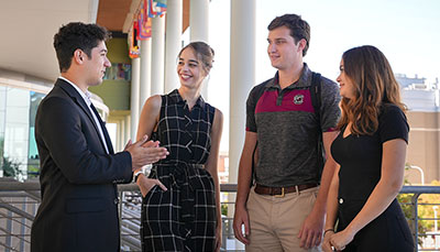 Group of business student standing outside of the Moore School.
