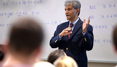 Professor standing in front of a class giving a lecture. 