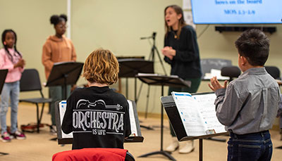 A teacher singing with a young group of students.